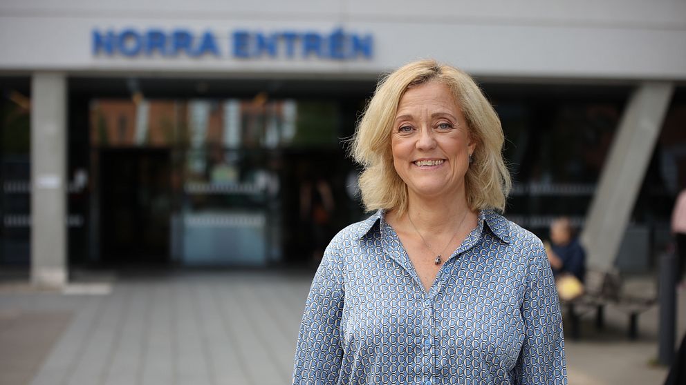 Kvinna i blå skjorta med mönster står framför universitetssjukhuset i LInköping