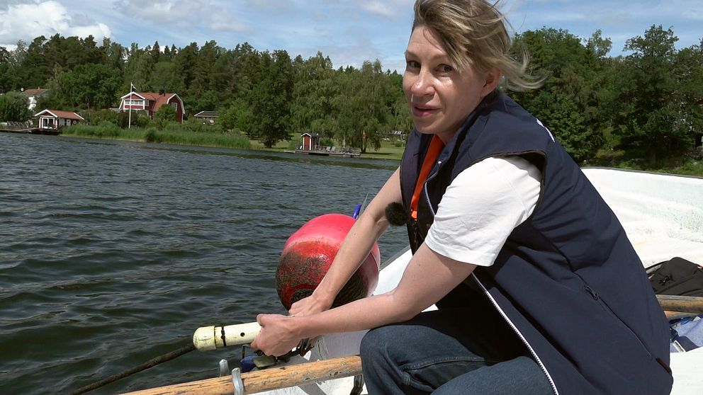 Kvinna i båt med mätinstrument.