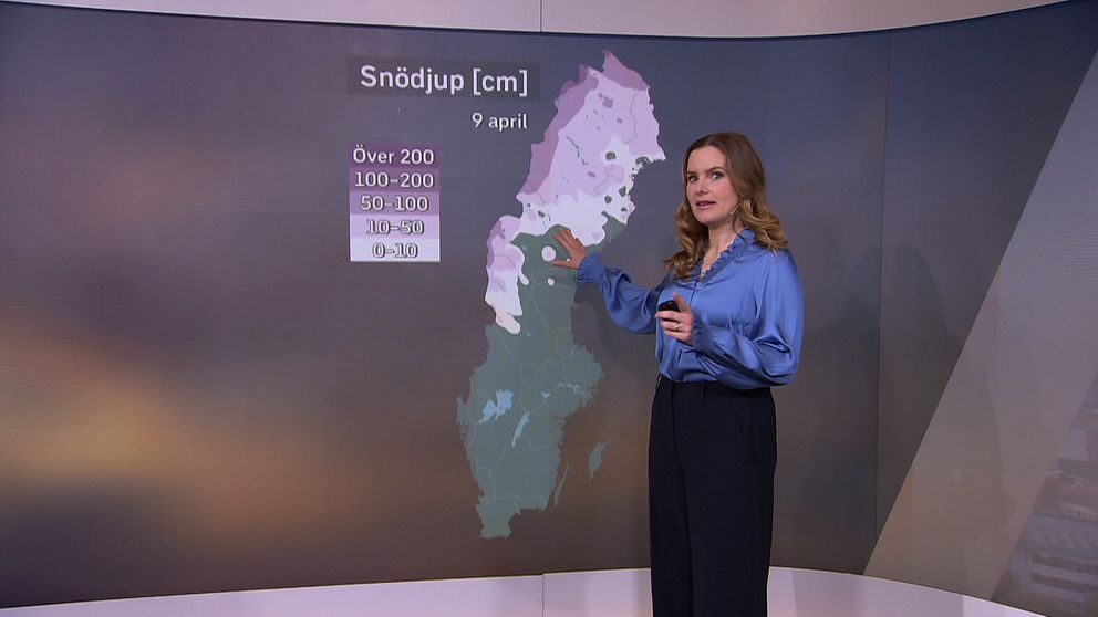 Meteorolog visar snödjupskarta över Sverige på en skärm.
