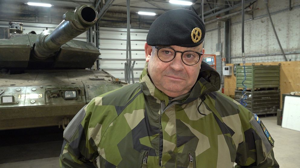 Michael Claesson i militäruniform står framför en stridsvagn inomhus.