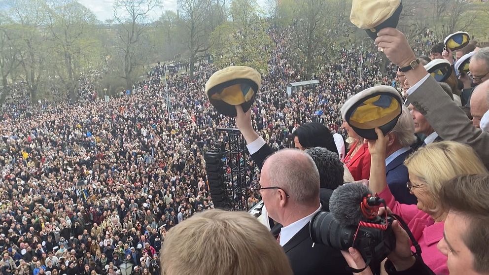 Personer med studentmössor i händerna och ett folkhav.