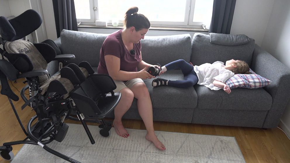 Mamma hjälper dotter som ligger i soffan på med sko