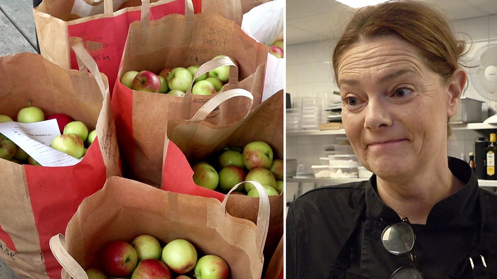 Flera papperspåsar fyllda med äpplen bredvid popologen Bibbi Kringlund i en köksmiljö på Kulinarika i Västra Ämtervik utanför Sunne, klädd i en svart kockrock med köksutrustning synlig i bakgrunden.