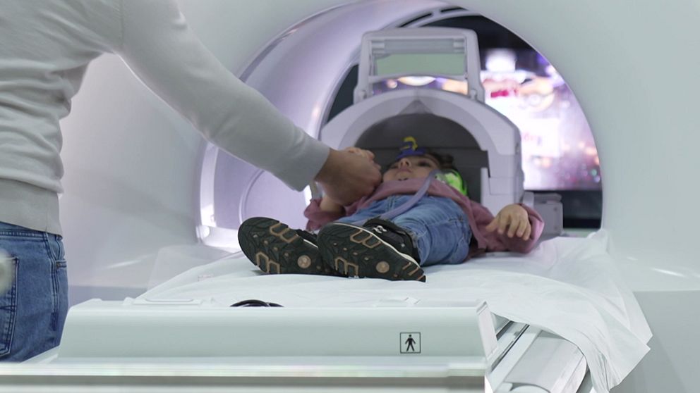 Ett barn åker in i en magnetröntgen-apparat.