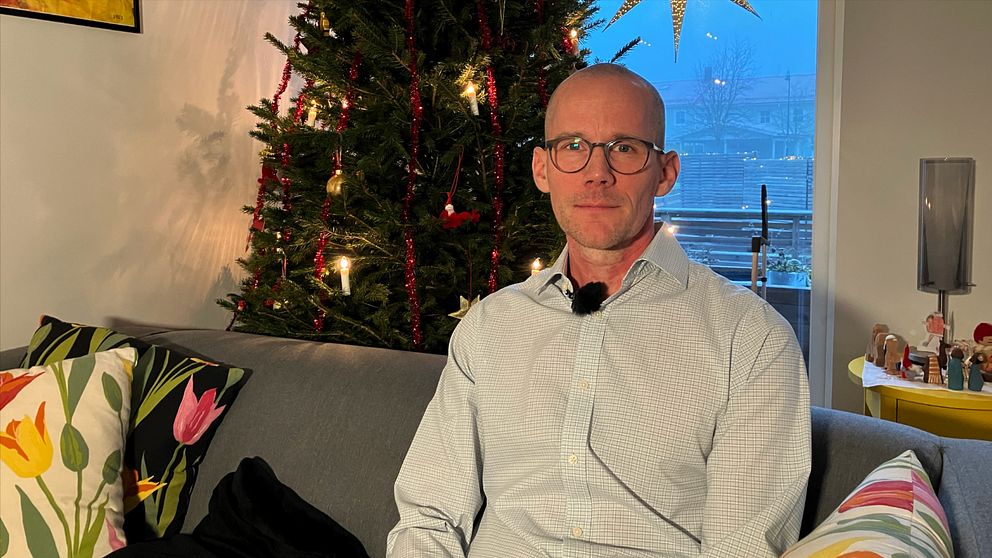 Man i glasögon framför julgran