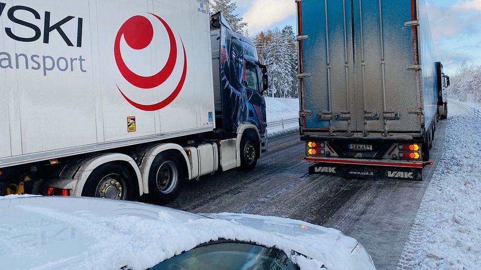Stopp i trafiken. Man ser stora lastbilar stå stilla på en snöig backe.