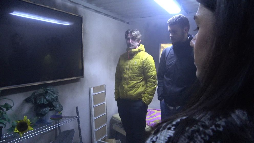 Två män och en kvinna står i ett rum där lamporna blinkar