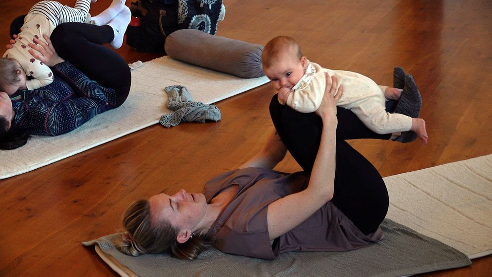 En mamma med sitt barn gör övningar på ett pass med bebisyoga i Falun.