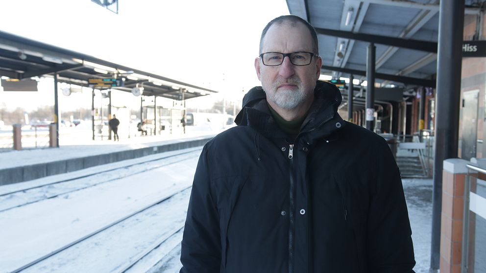 Man i svart vinterjacka och svarta glasögon står på perrongen vid Linköpings resecentrum.