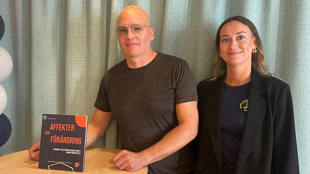Patrik Nordell och Josefine Backlund står vid ett bord med en bok om forumteater.