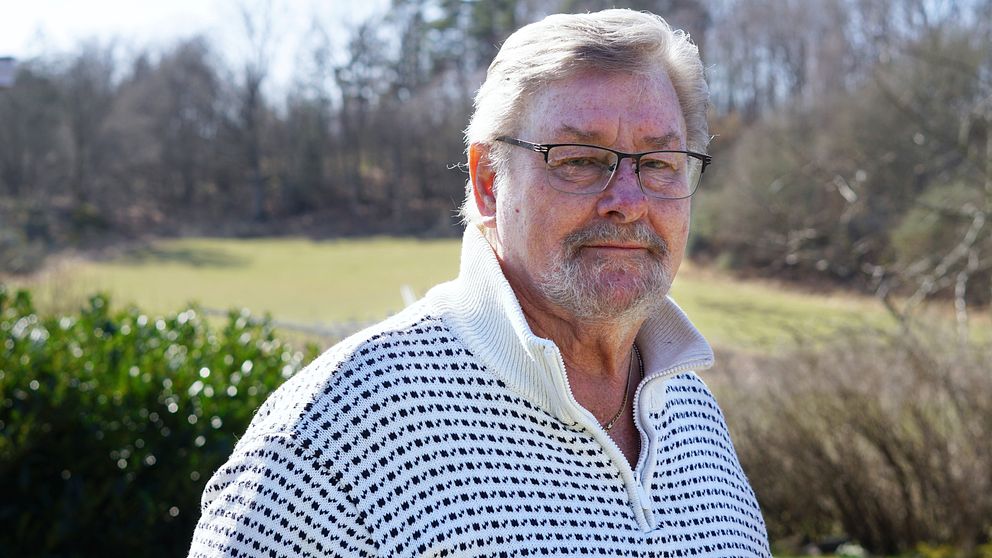 Prostatacancersjuka Keith Olsson med vit tröja står utomhus en solig vårdag. han berättar vad han tänker om att alla cancerspecialister slutat i Blekinge.