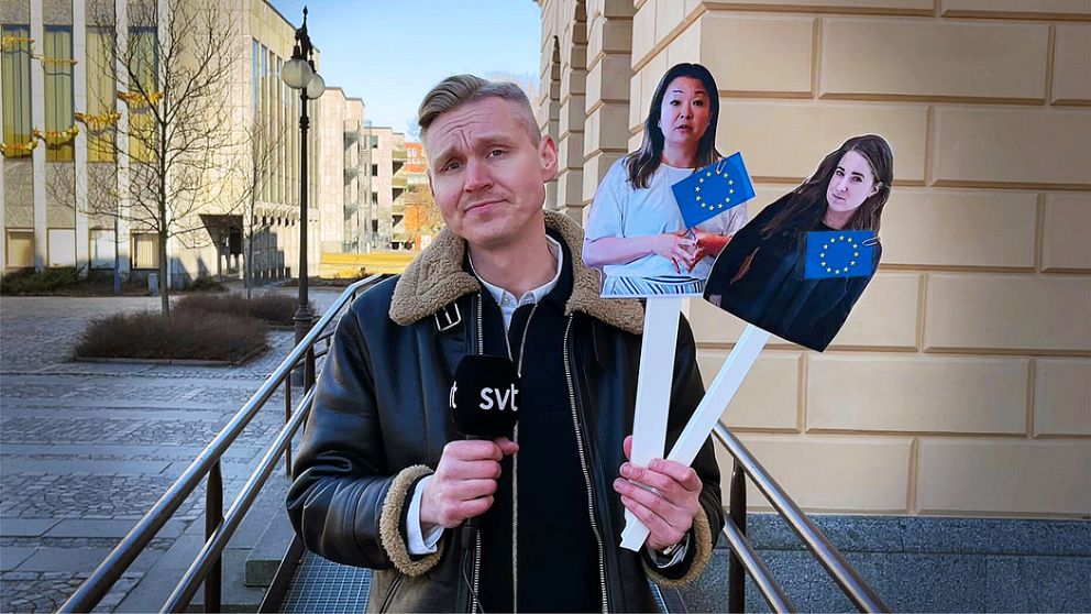 Reporter håller upp två figurutklippta bilder som är uppklistrade på varsin pinne som reportern håller i. På bilderna syns två kvinnliga EU-politiker.