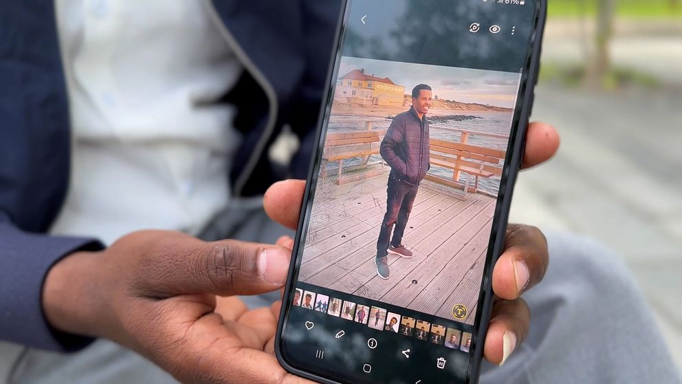 Man håller upp mobiltelefon och visar ett fotografi.