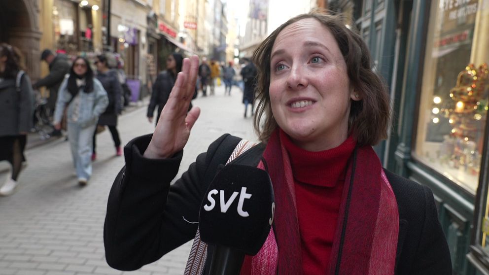 Person intervjuas av SVT på en gågata med butiker och förbipasserande i bakgrunden.