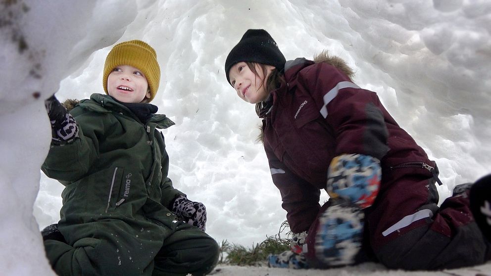 Två förskolebarn leker i en igloo