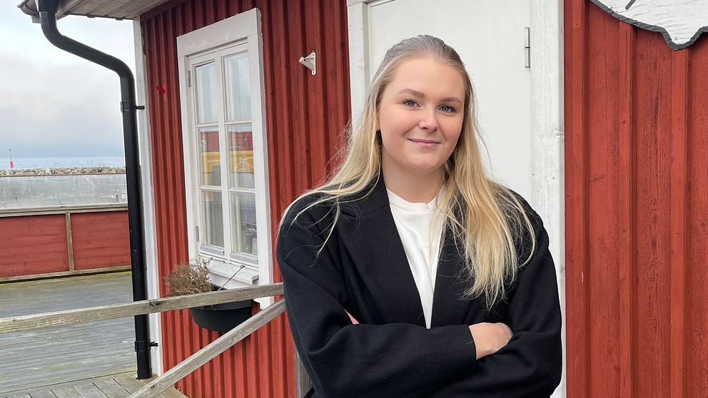 Jasmine Nilsson äger restaurangen Fiskerian i Hörvik. På bilden står hon utomhus med armarna i kors, hon står framför ett rött hus och tittar in i kameran.