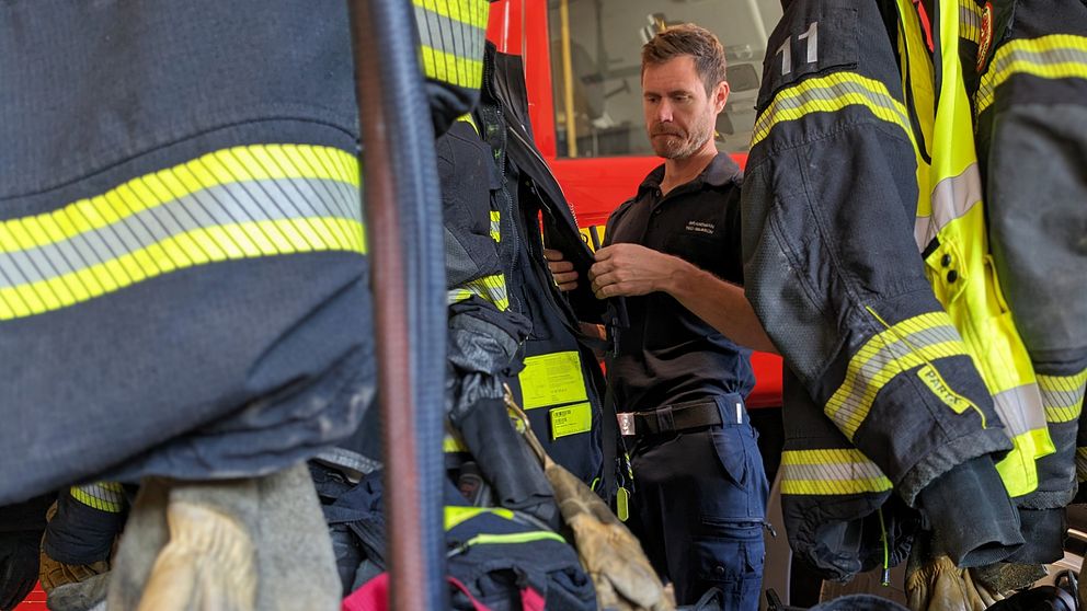 Arbetsplatsombudet och brandmannen Ted Nilsson står invid en brandbil och inspekterar brandutrustning