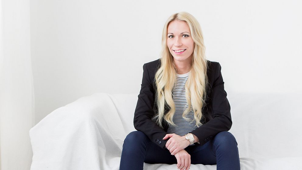 Jacqueline Joo sitter i en vit soffa, med en vitt vägg bakom sig.