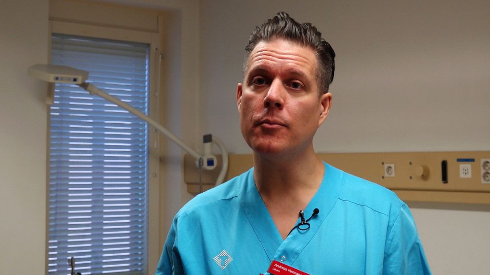 Sjukvårdspersonal i blå uniform står i ett rum med medicinsk utrustning.