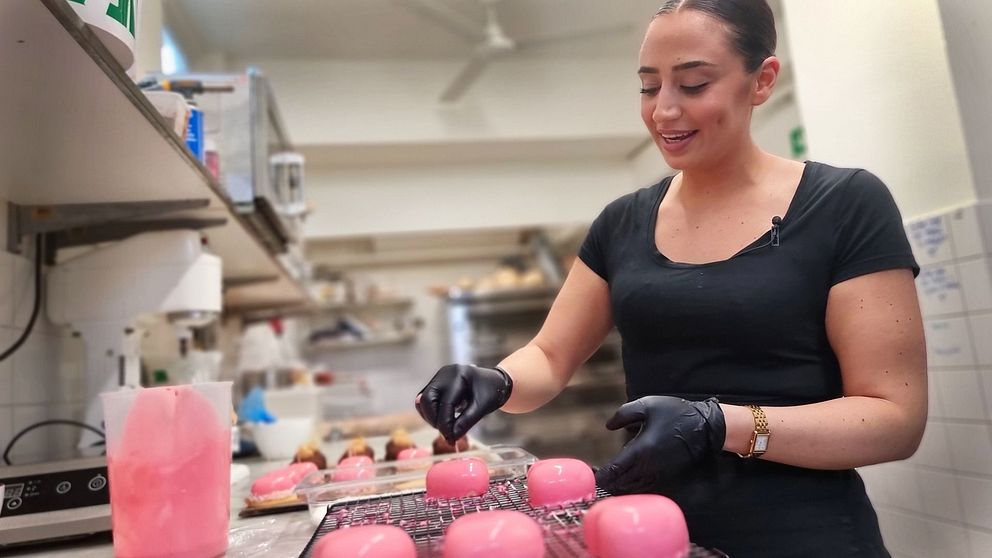 Kvinna gör rosa bakelser i ett kök.