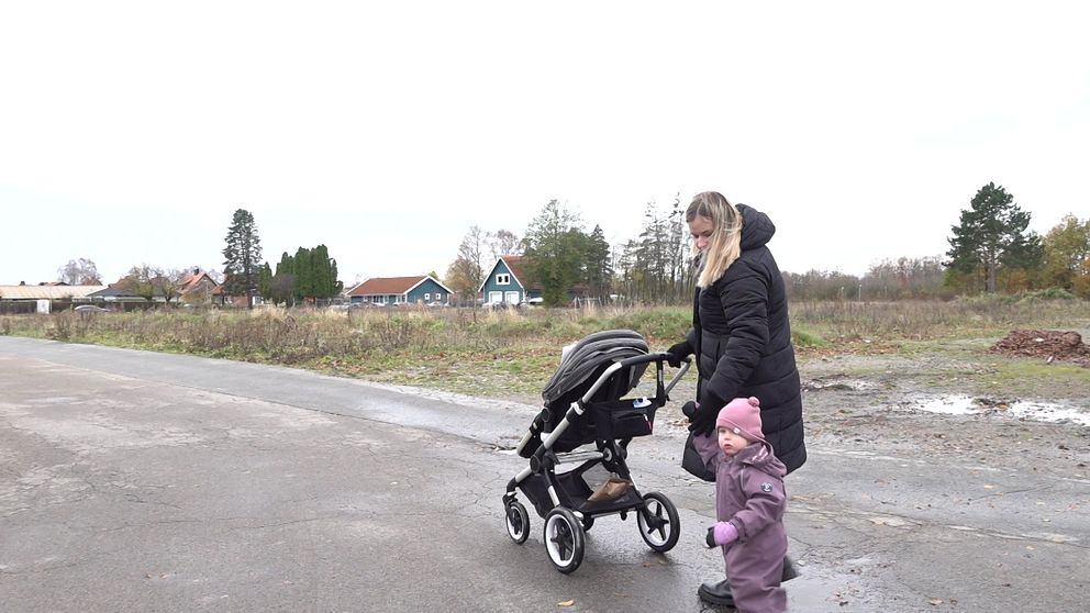 En mamma med barnvagn och barn.