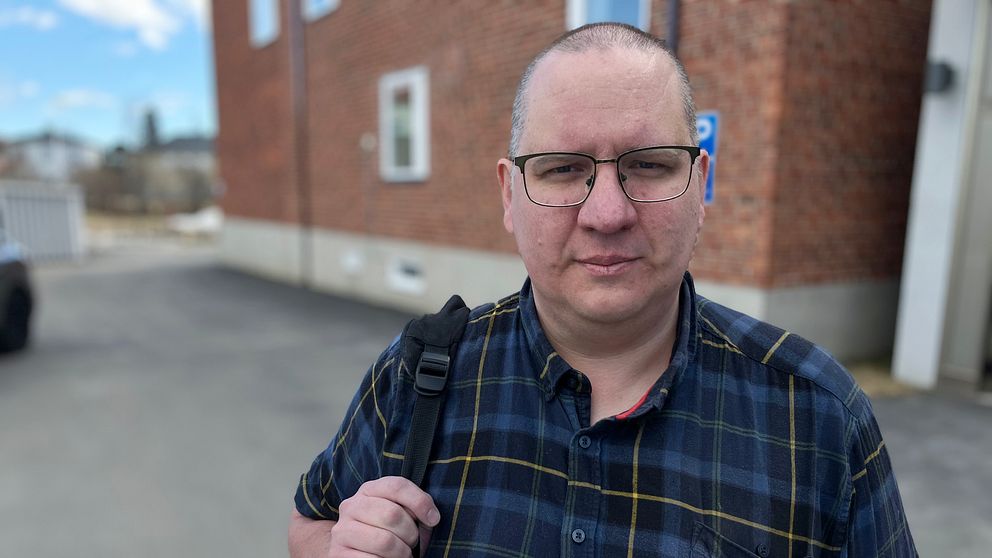 Åklagare Jonas Fjellström – en medelålders man i flanellskjorta och glasögon framför en tegelbyggnad