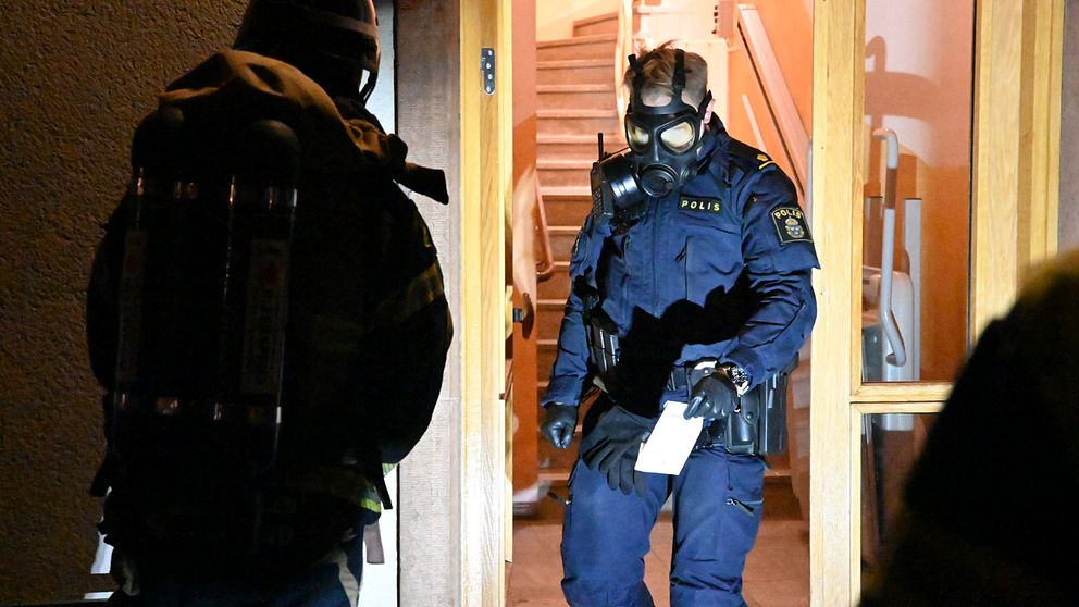 Polis med skyddsmask arbetar vid trapphus efter utsläpp av okänd vätska.