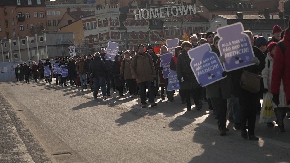 Protestmarsch med människor som bär skyltar.