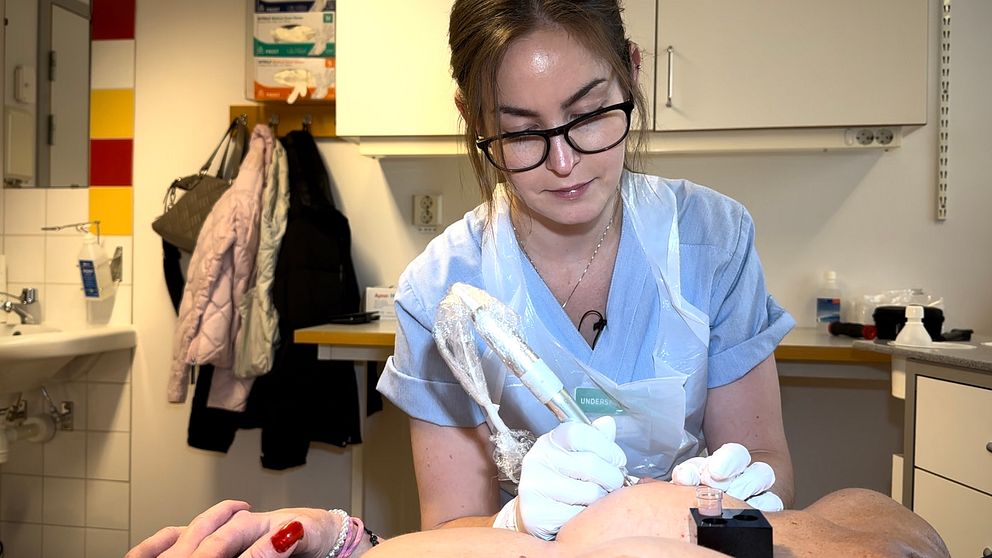 Undersköterskan Viktoria Philman sticker en tatueringspenna mot ett kvinnobröst.