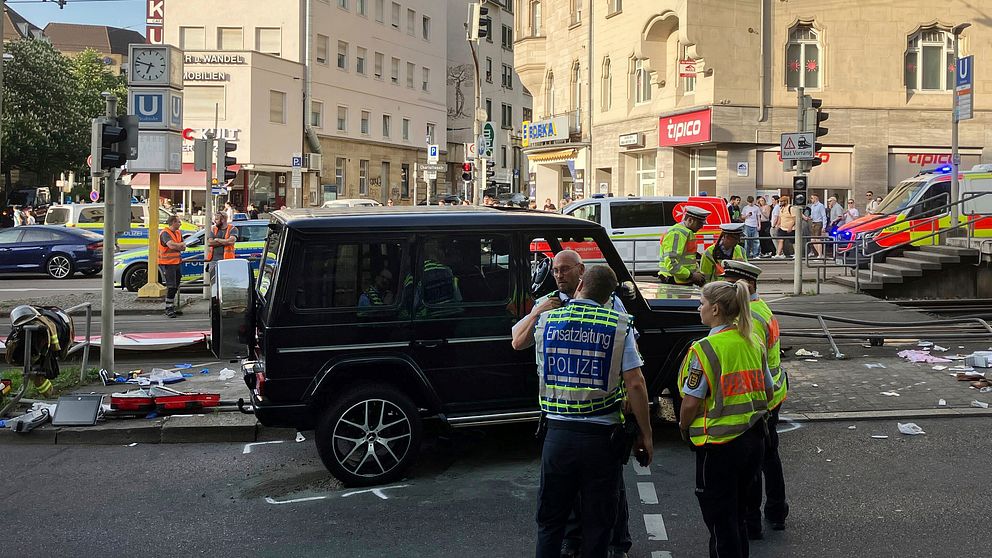 Poliser och räddningstjänst vid en svart SUV efter trafikolycka i stadsområde.