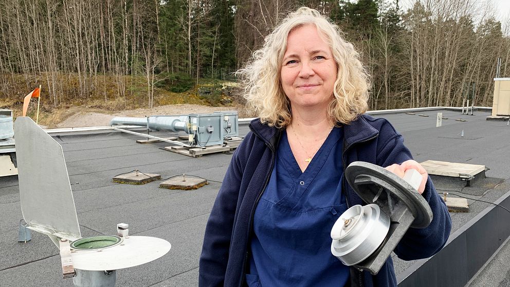 Susanne Fröjdendal står på ett tak och håller i en pollenfälla.