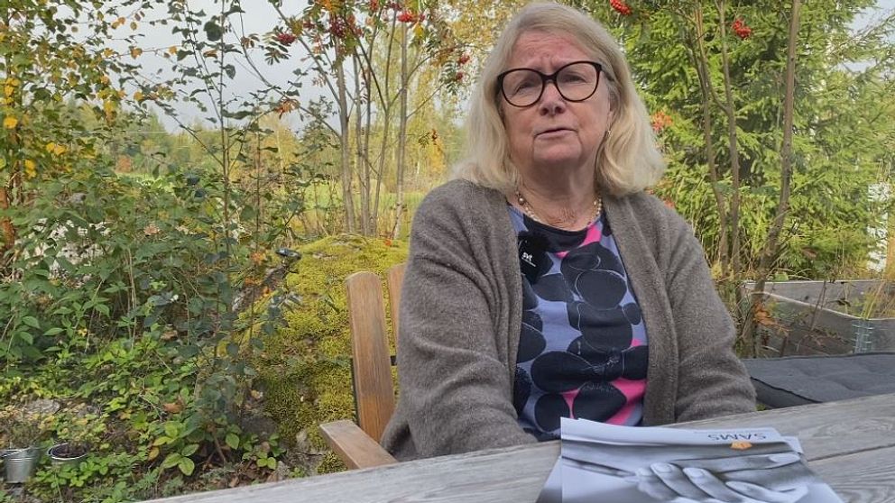 Anna-Lena Söderlund Törnell sitter vid ett bord utomhus med en rapport framför sig