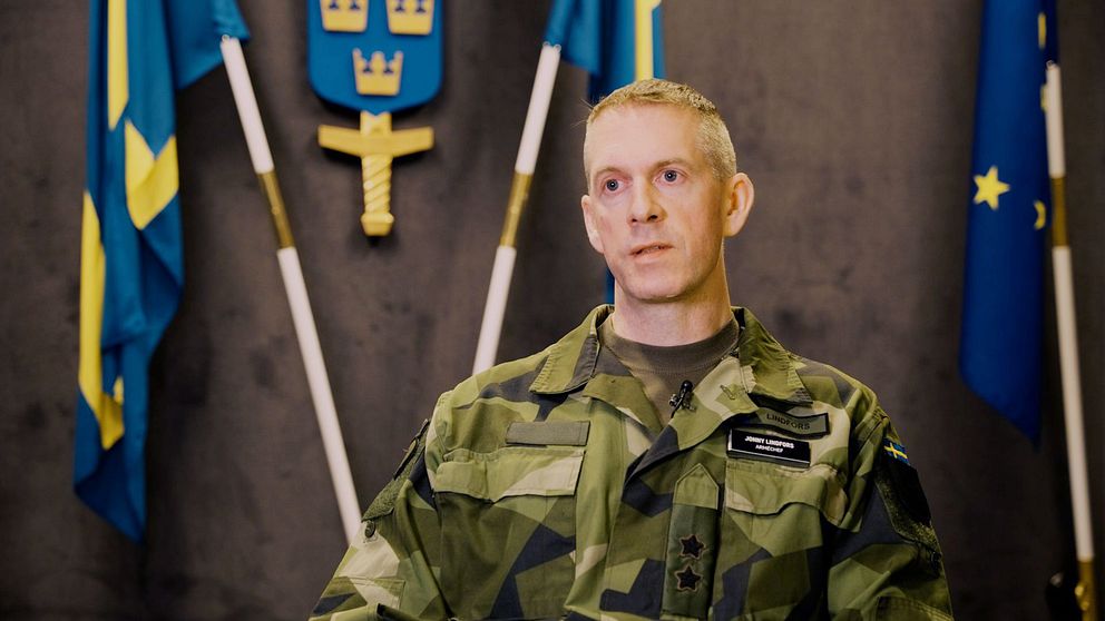 arméchefen Jonny Lindfors framför en svensk flagga