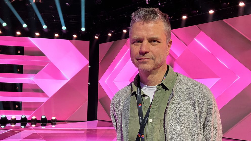 Melodifestivalens projektledare står på scenen och tittar in i kameran
