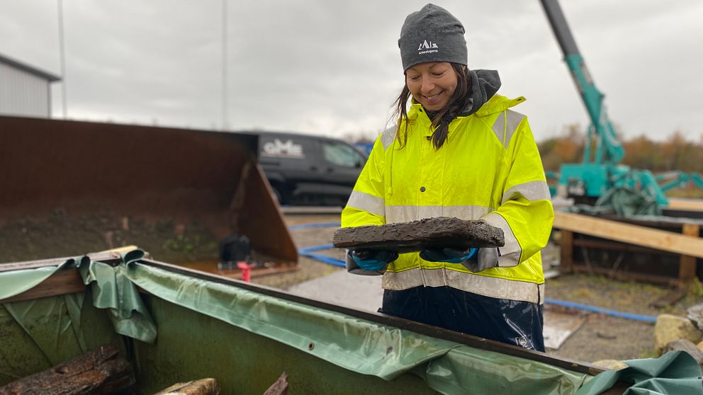 Kvinna hållandes i vrakdel från 1300-talsfartyg.