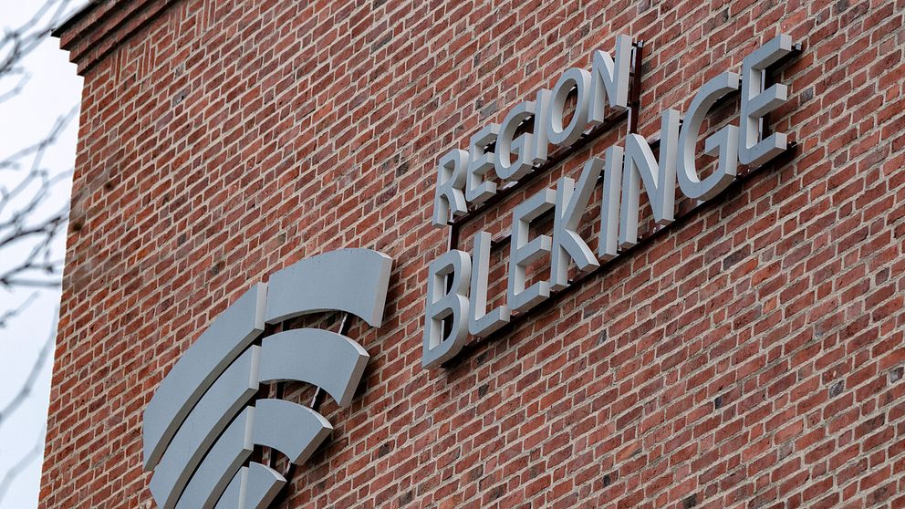 Skylt med texten ”Region Blekinge” i metallisk stil, placerad på en tegelvägg.
