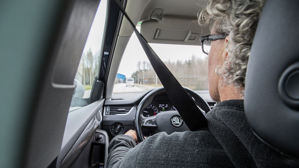 En man sitter vid ratten och kör bil