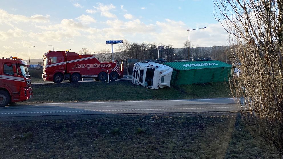 En lastbil ligger på sidan på en påfart till motorväg
