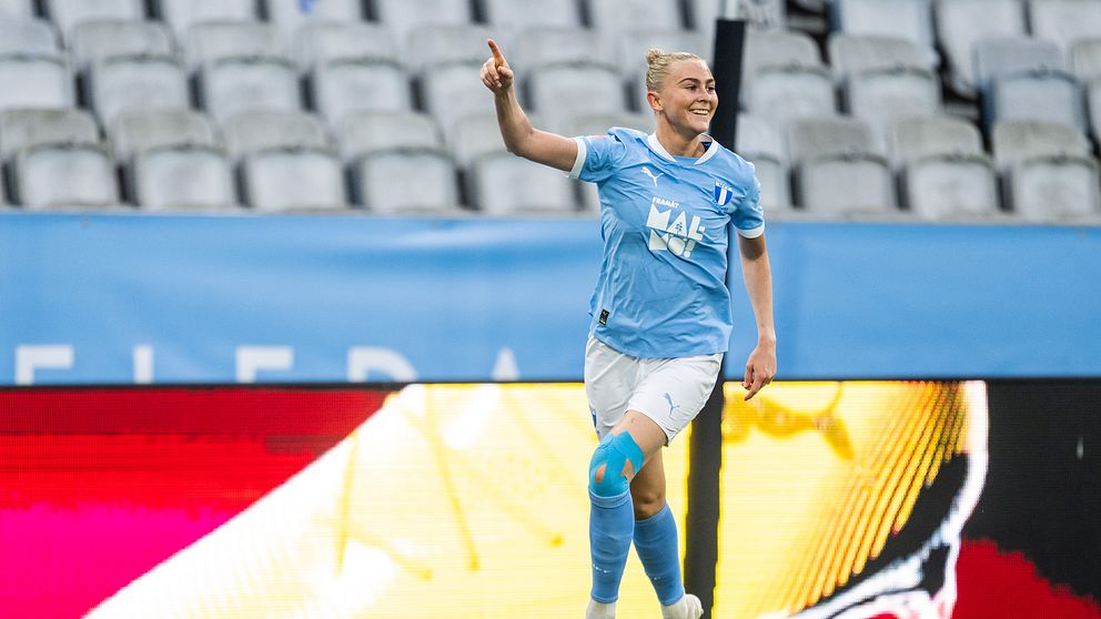 Fotbollsspelare i ljusblått firar ett mål på en nästan tom arena.