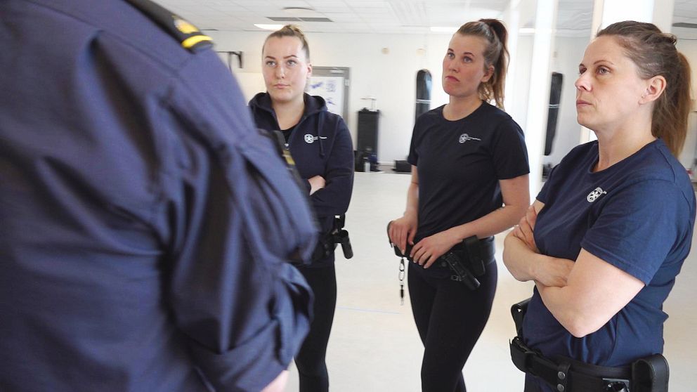 Poliselever står och lyssnar på instruktör.