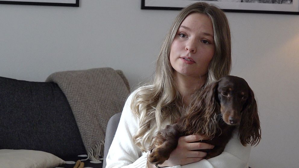 Emilia Nilsson, matte till dvärgtaxen Cooper. håller sin hund i famnen.