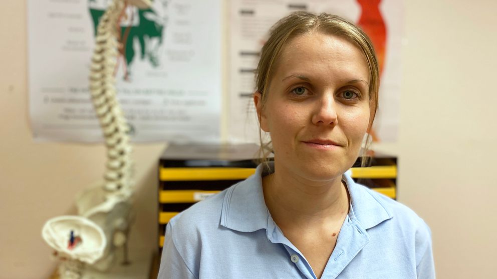 Porträttbild på fysioterapeuten Amanda Björkeng Betzholtz. I bakgrunden skymtar en atrapp föreställande en ryggrad.