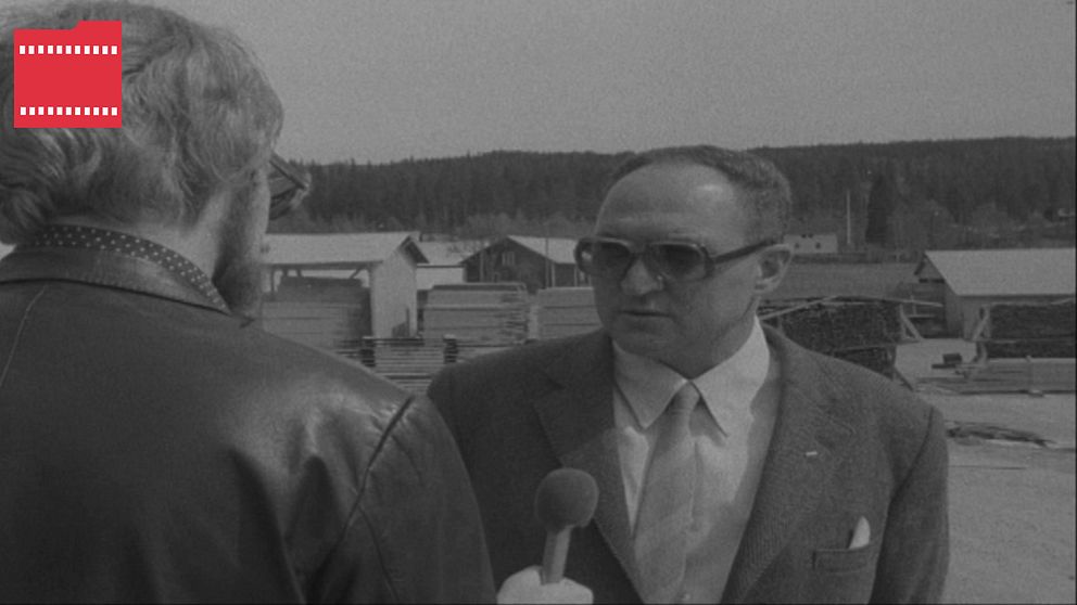 en man står och blir intervjuad av en reporter – svartvit bild