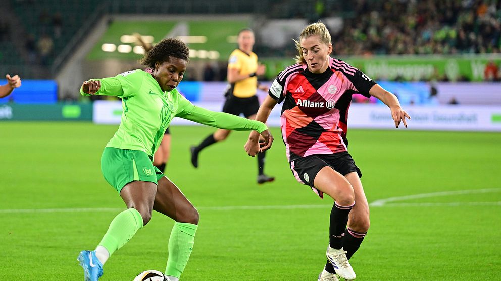 Två damfotbollsspelare i kamp om bollen under en match på en gräsplan.