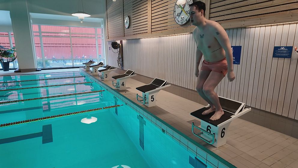 Christoffer Johansson förbereder hopp från startblock vid en simbassäng.