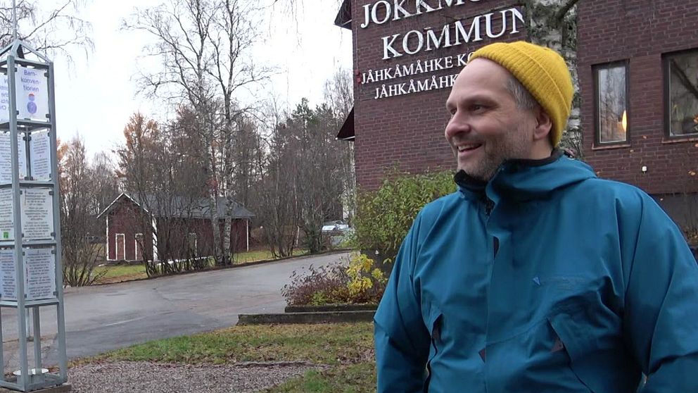 Henrik Blind utanför kommunhuset i Jokkmokk, klädd i blå jacka och gul mössa.
