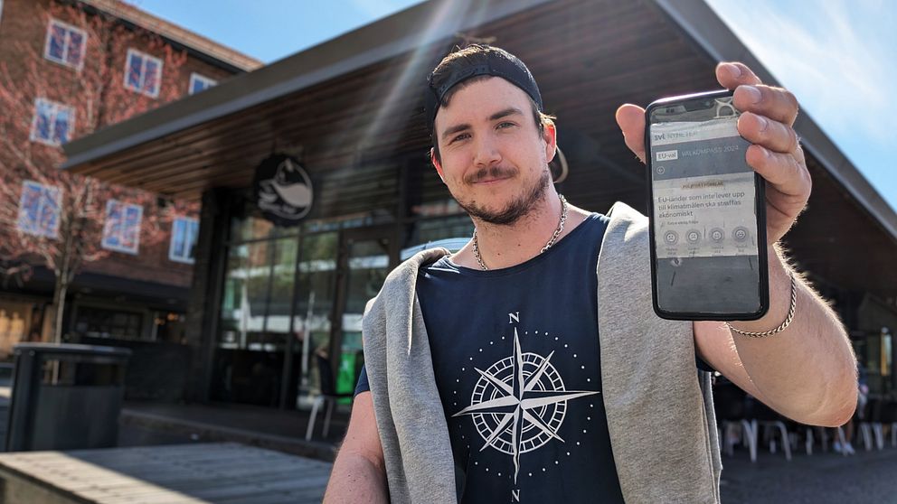 Tor Hettinger  visar upp mobilen i solen på torget i Umeå – en sida från EU-valkompassen syns på skärmen