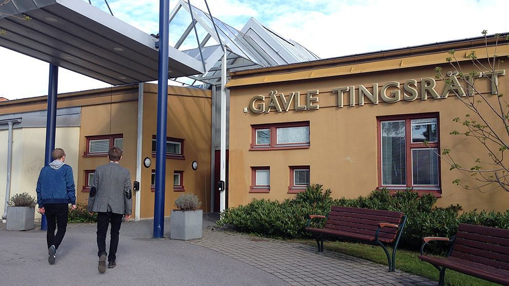 Två kostymklädda män går in i Gävle tingsrätts gula byggnad.