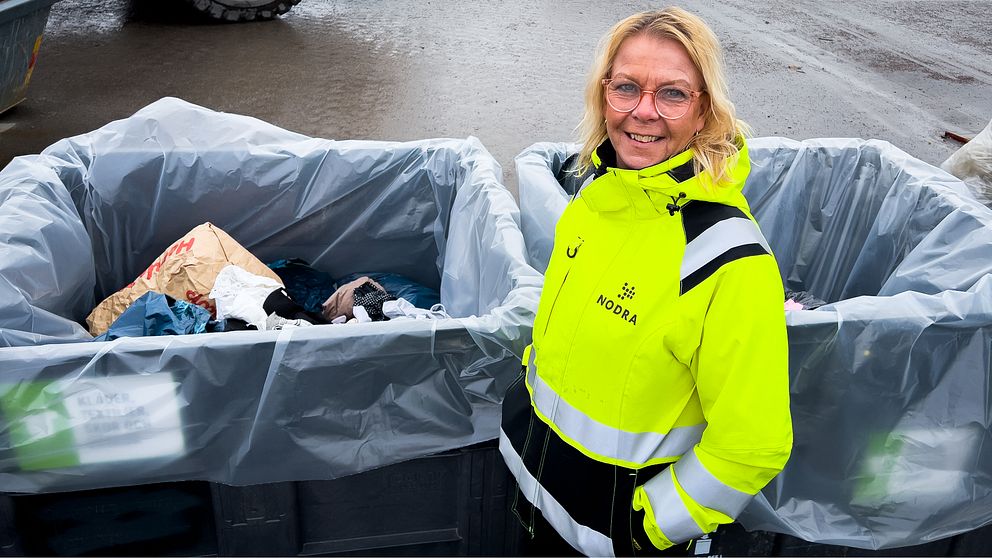 Person i reflexjacka vid två stora sopcontainrar.