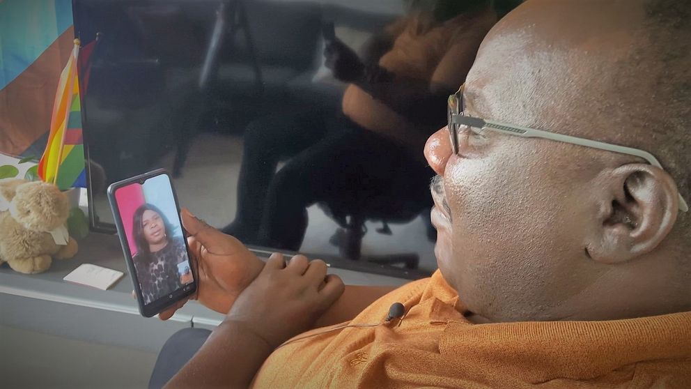 Prästen Edwin Sikot sitter i videosamtal med transperson i Uganda